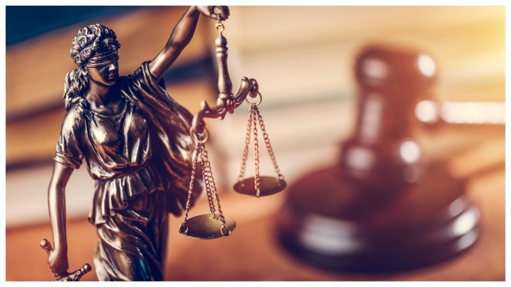 Gold Law scale with a judge's gravel faded in the background.